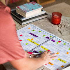 Person playing Scrabble with a colorful board and tiles on a table.
